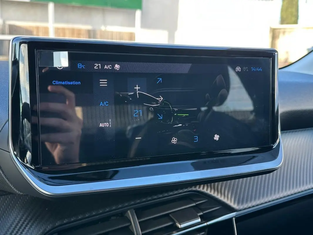 Écran tactile du système de climatisation dans l’habitacle d’une Peugeot 208 blanc, vue de face.