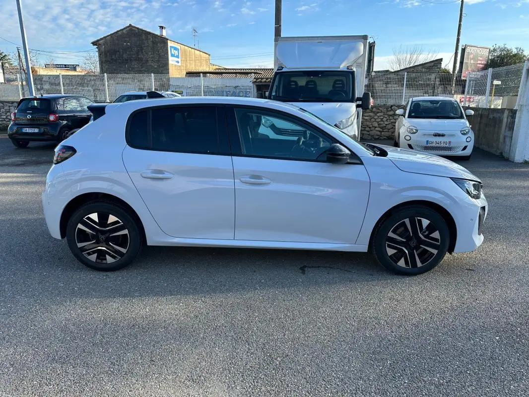 Profil droit d'une Peugeot 208 Hybrid 110 e-DCS6 Allure blanche avec jantes alliage noires et toit noir.