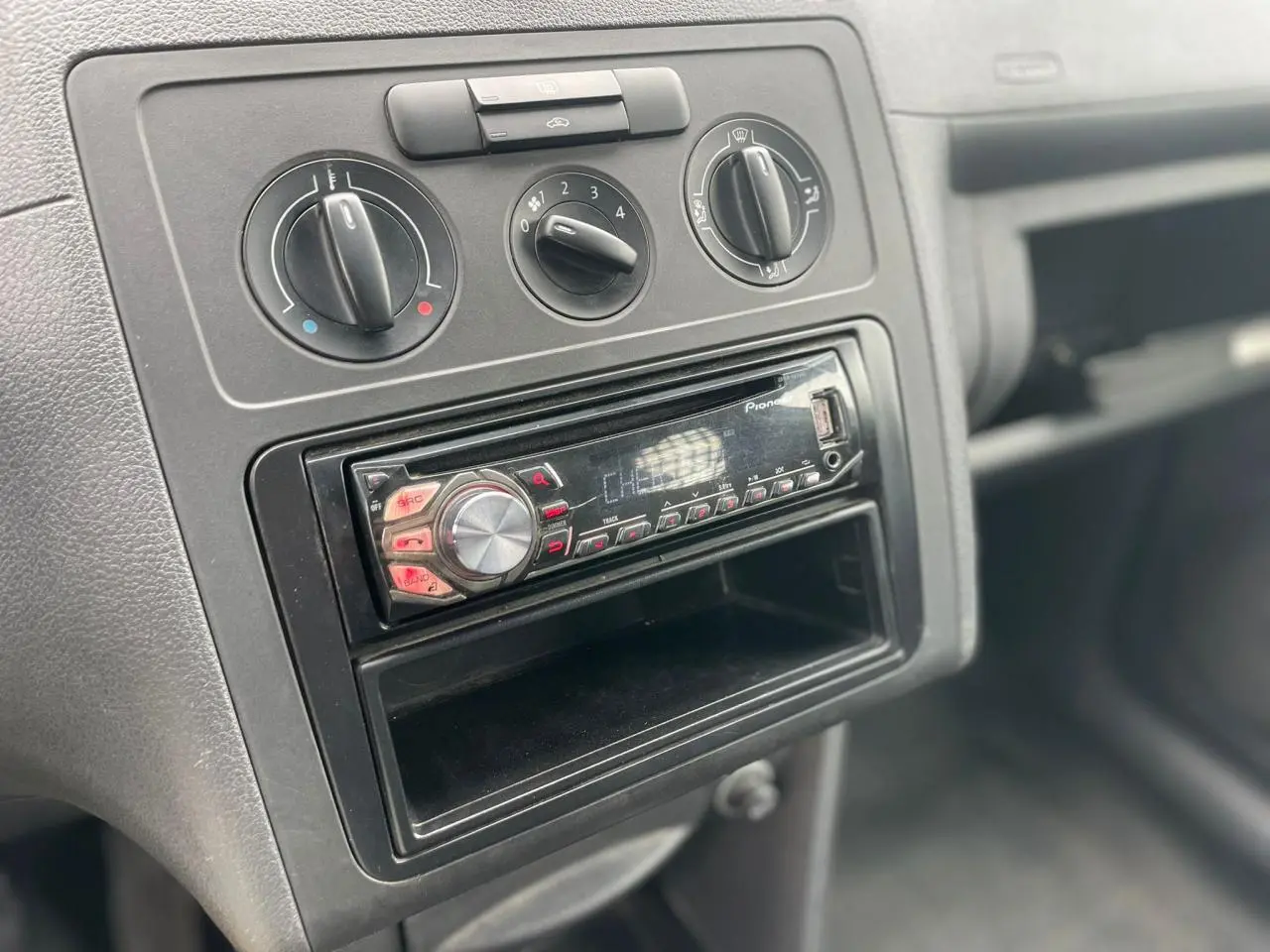 Gros plan sur la console centrale du Volkswagen Caddy 2014 avec commandes de climatisation et radio Pioneer.