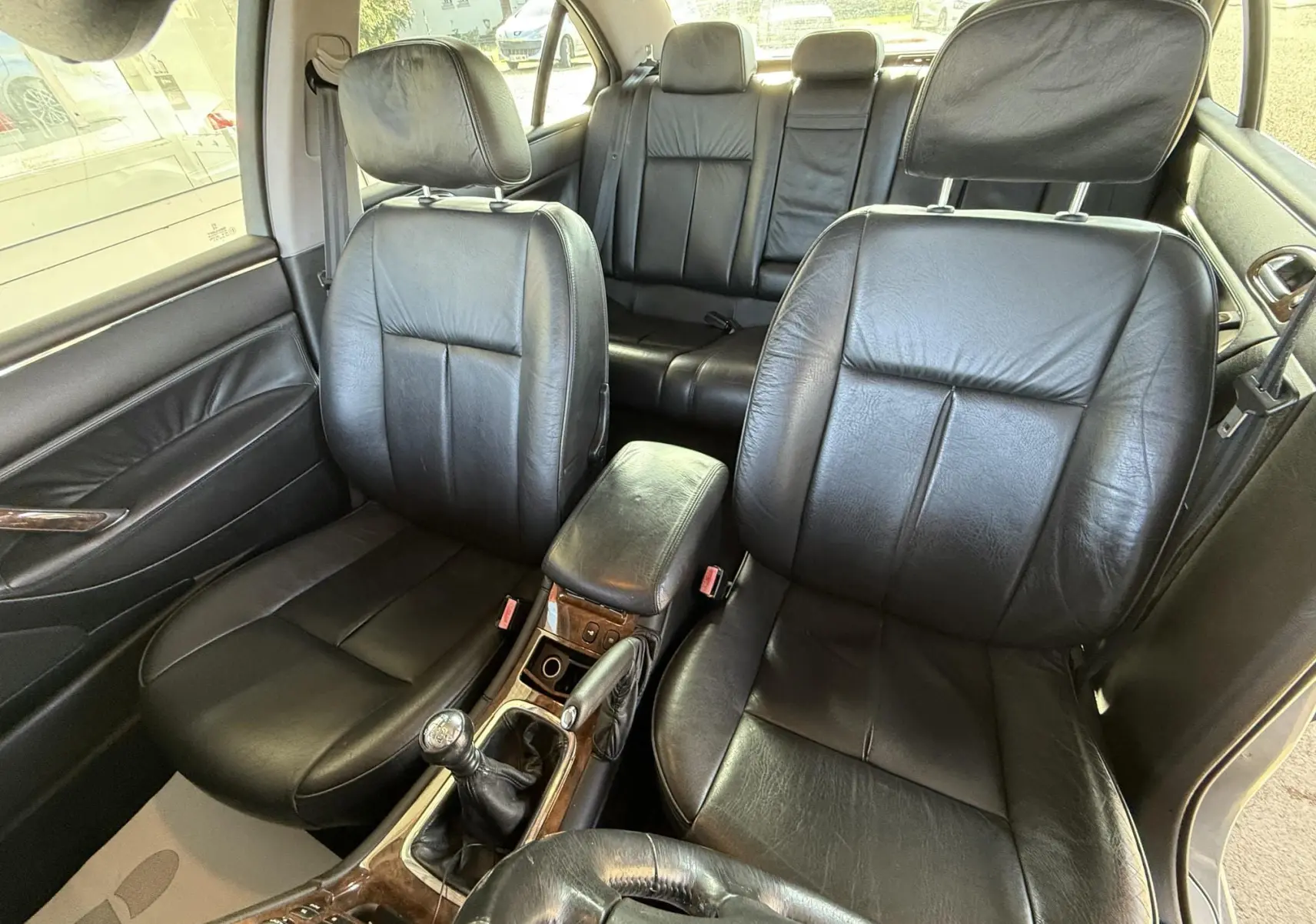 Vue intérieure rapprochée des sièges avant en cuir noir et de la console centrale d'une Peugeot 607 gris.