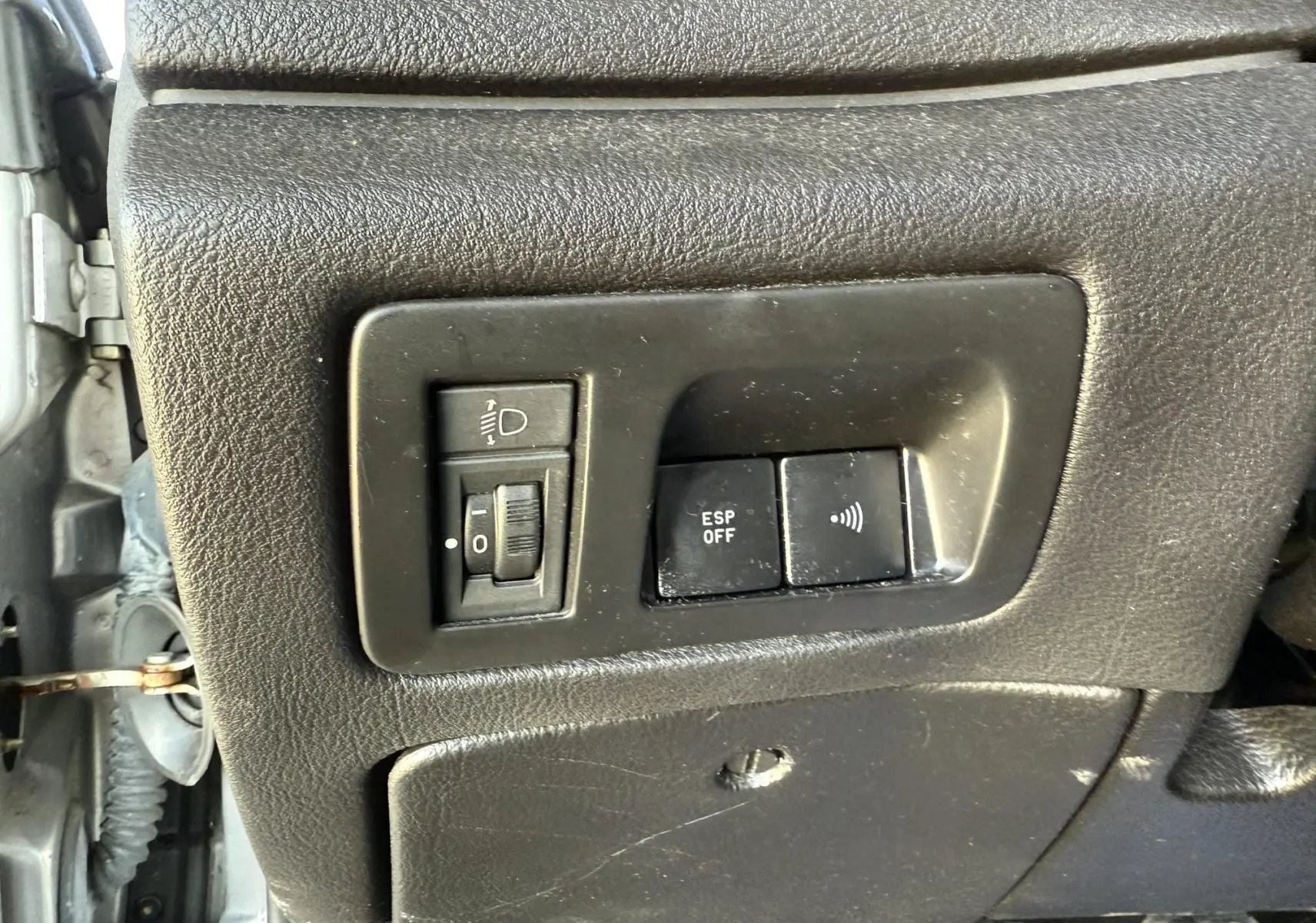 Gros plan sur les commandes noires du tableau de bord côté gauche d'une Peugeot 607 gris, avec réglage éclairage et bouton ESP off.