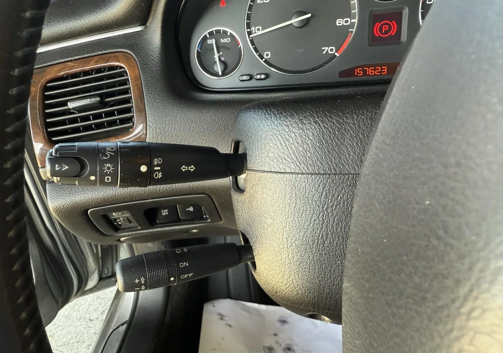 Gros plan sur le tableau de bord et les commandes au volant d'une Peugeot 607 gris, avec compte-tours et témoins lumineux visibles.