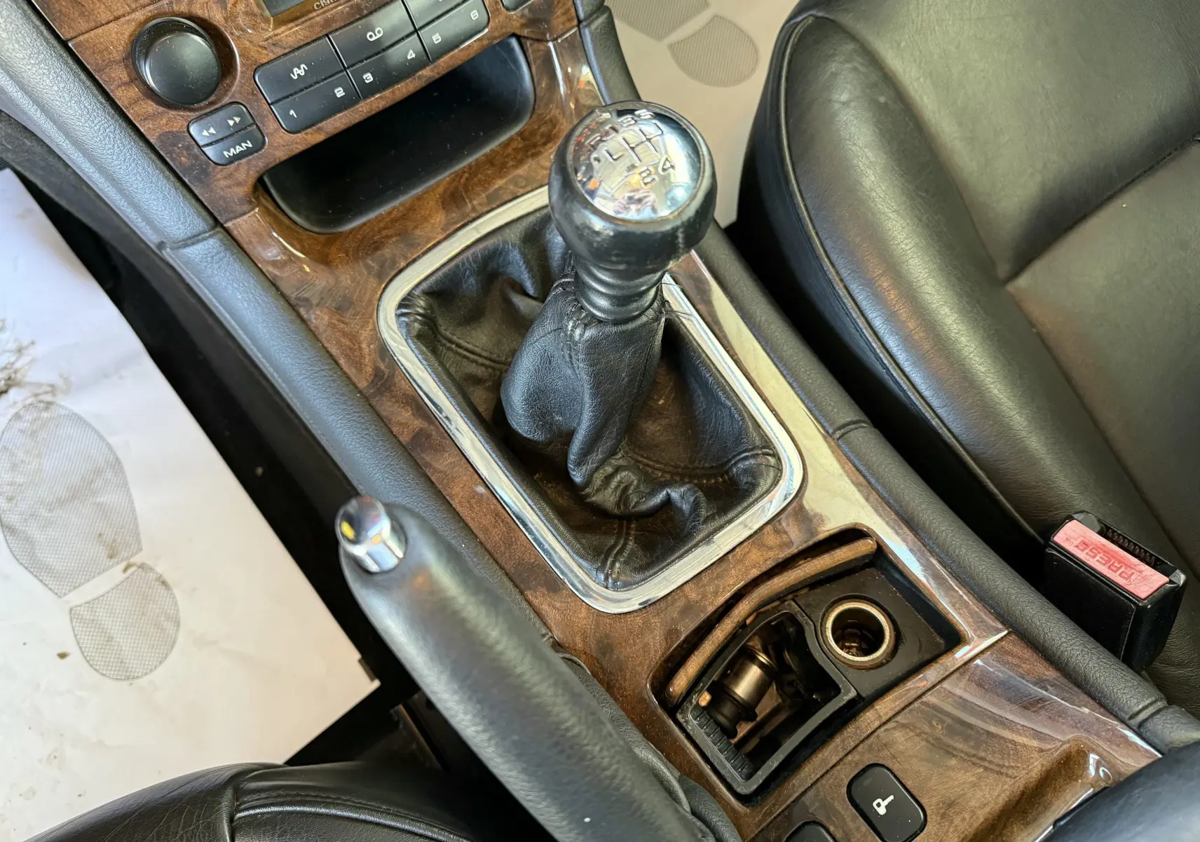 Gros plan sur la console centrale en bois avec levier de vitesse manuel et siège cuir noir d'une Peugeot 607 gris.