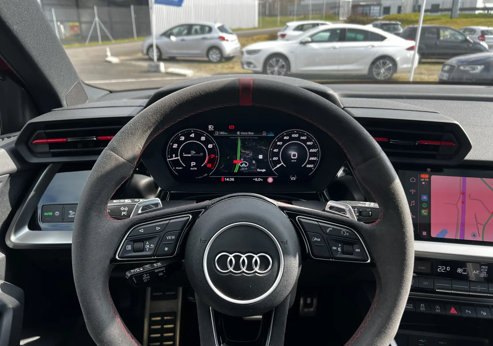 Vue intérieure centrée sur le volant sport en alcantara avec surpiqûres rouges de l'Audi RS3 Sportback rouge 2022.