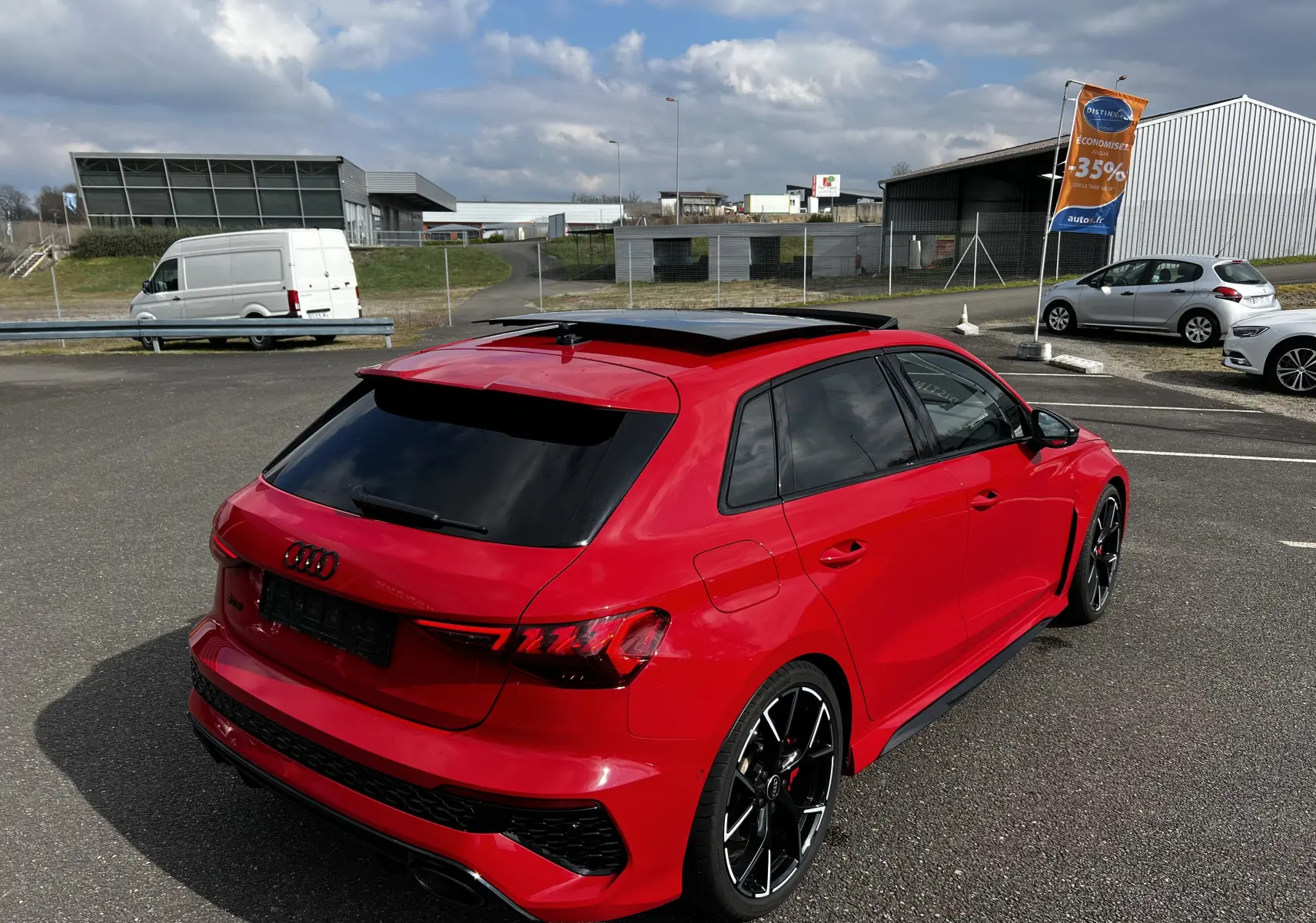 Audi RS3 Sportback rouge vue 3/4 arrière droit avec jantes noires et toit ouvrant panoramique.
