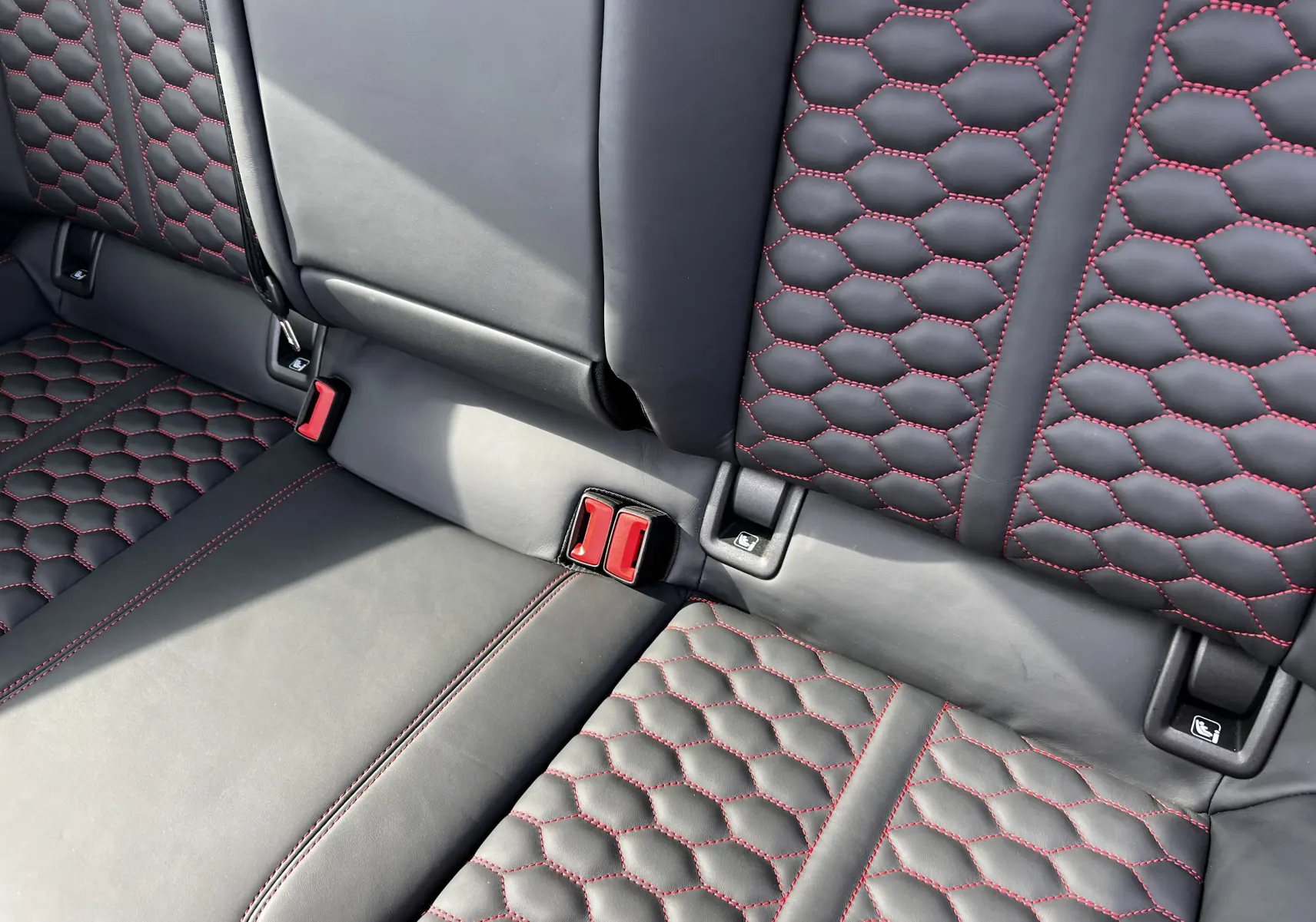 Détail des sièges arrière en cuir noir avec surpiqûres rouges en nid d'abeille de l'Audi RS3 Sportback 2022.