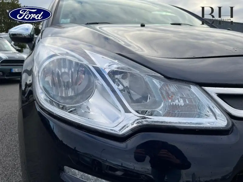 Gros plan sur le phare avant gauche d'une Citroën C3 bleu encre, soulignant les détails du bloc optique et la carrosserie brillante.