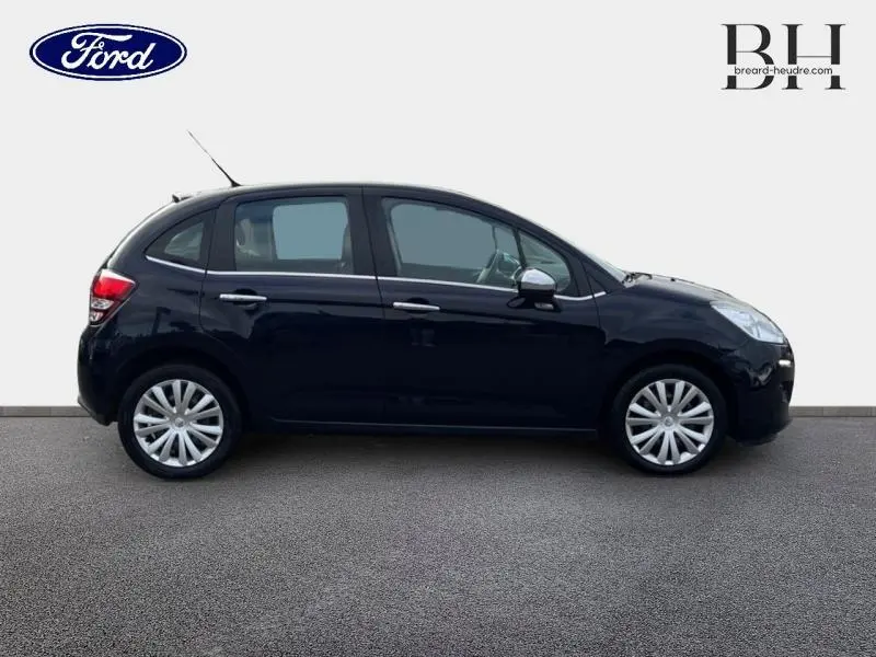 Profil côté gauche d'une Citroën C3 bleu encre 2014 avec jantes argentées et poignées chromées visibles.