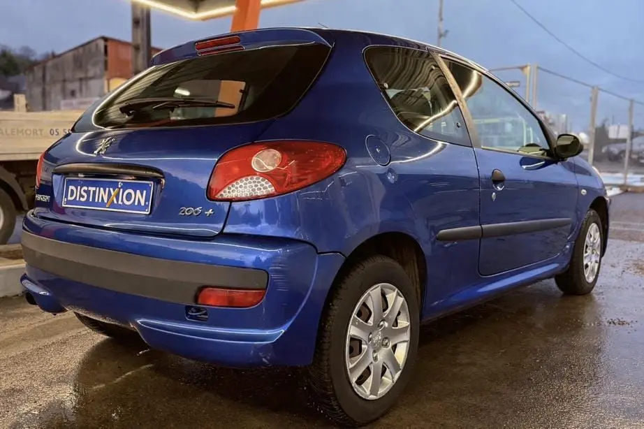 Vue 3/4 arrière droite d'une Peugeot 206+ bleue 3 portes, avec feux arrière rouges et jantes argentées.