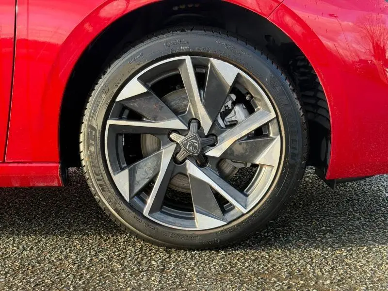 Gros plan sur la roue avant gauche de la Peugeot 308 2024 rouge Elixir avec jante alliage au design moderne.
