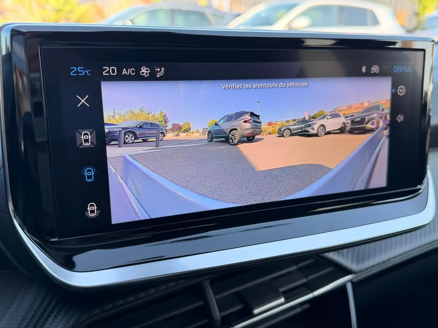 Écran tactile intérieur montrant la caméra de recul avec vue arrière sur plusieurs véhicules en stationnement.