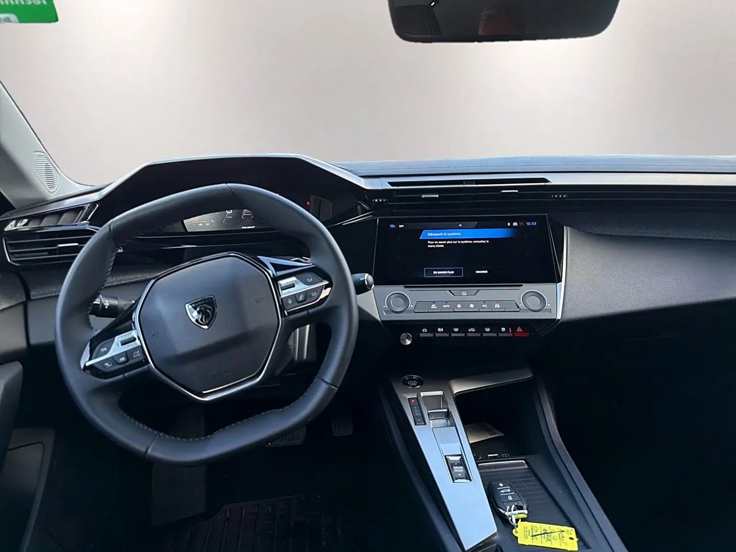 Intérieur de la Peugeot 308 2025, vue du poste de conduite avec volant multifonction et écran tactile central.