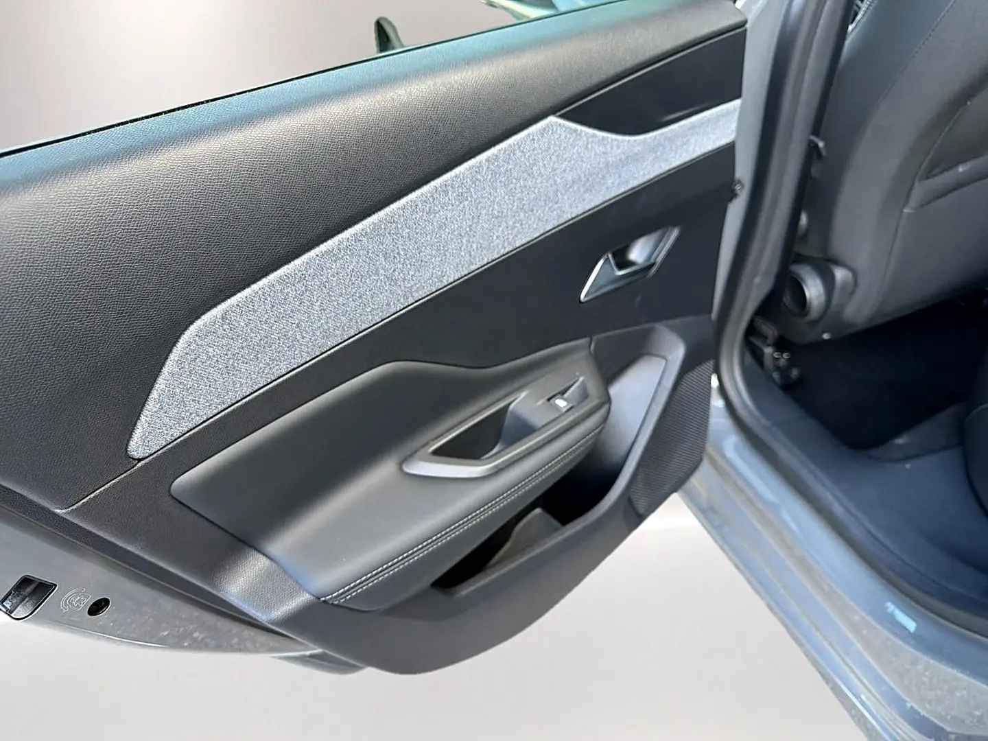 Vue rapprochée de la porte arrière gauche gris selenium de la Peugeot 308 2025 avec garniture textile et plastique noir.