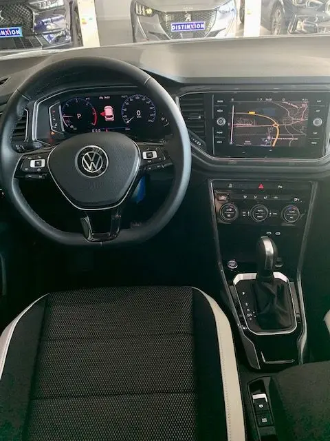 Vue intérieure du Volkswagen T-Roc 2021 montrant le volant noir, tableau de bord digital et écran central avec navigation.