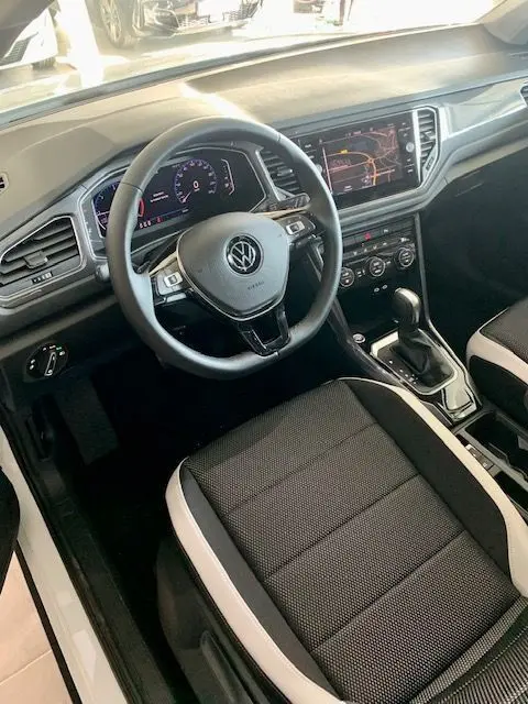 Vue intérieure côté conducteur du Volkswagen T-Roc 2021, tableau de bord numérique et sellerie noire avec surpiqûres claires.