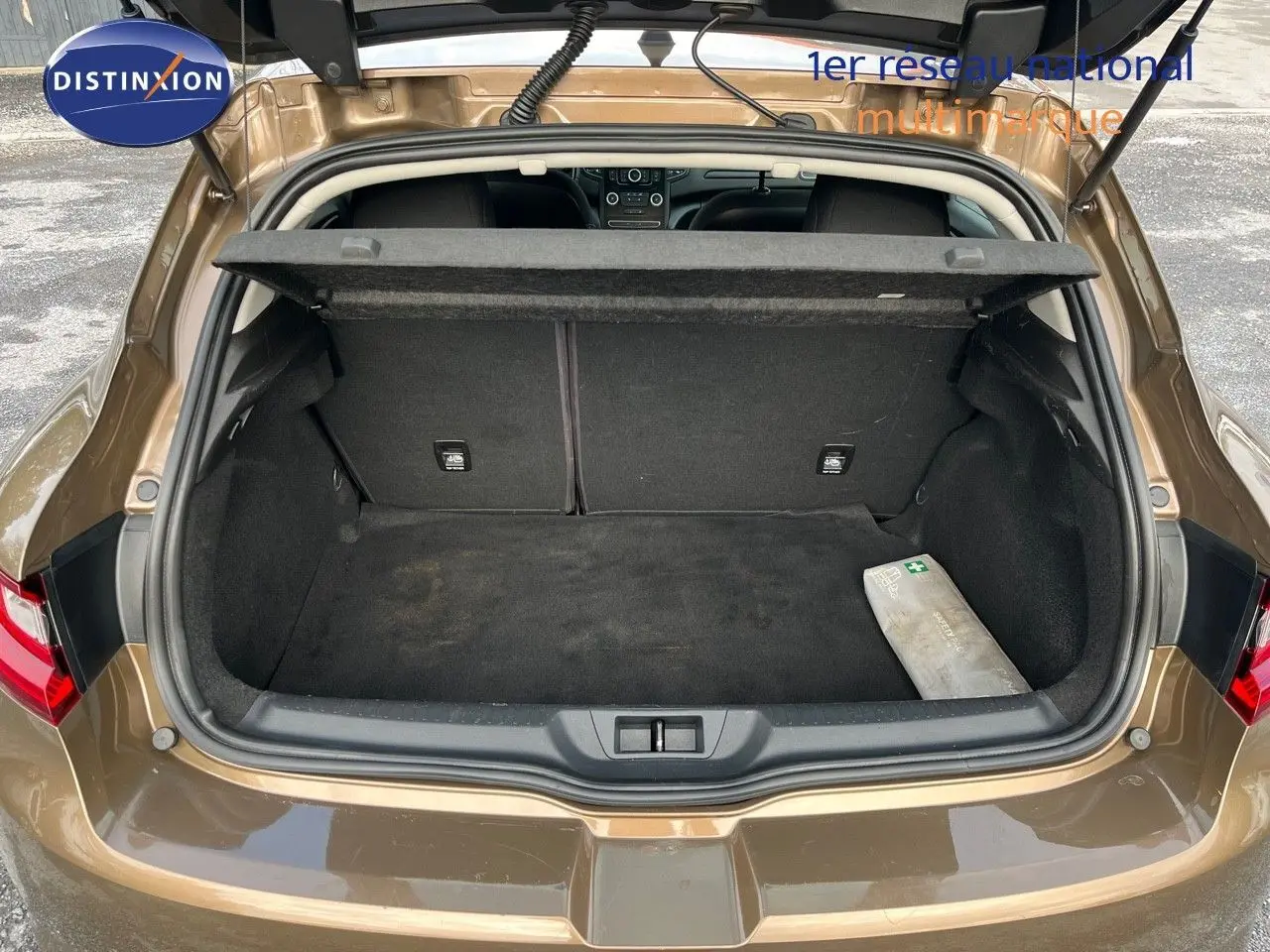 Coffre ouvert vu de l'arrière d'une Renault Mégane IV brun Capuccino, montrant un espace de rangement propre avec cache-bagages.