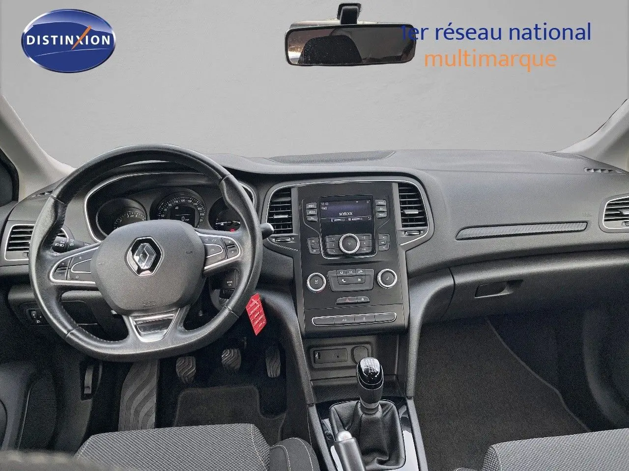 Vue intérieure frontale du tableau de bord et volant noir d’une Renault Mégane IV TCe 100 CH LIFE de 2016 avec boîte manuelle.