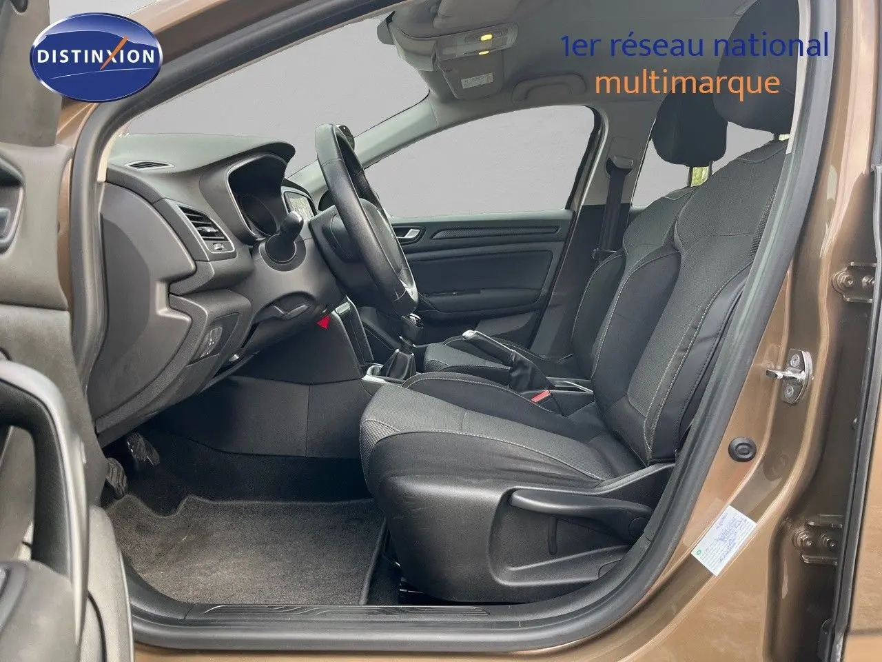 Vue intérieure côté conducteur de la Renault Mégane IV brun cappuccino, montrant les sièges tissu et la boîte manuelle.