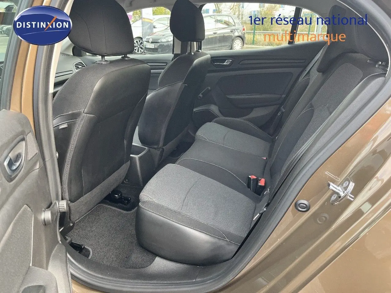 Vue côté gauche arrière de l'habitacle d'une Renault Mégane IV brun cappuccino, sièges tissu noirs et gris visibles.