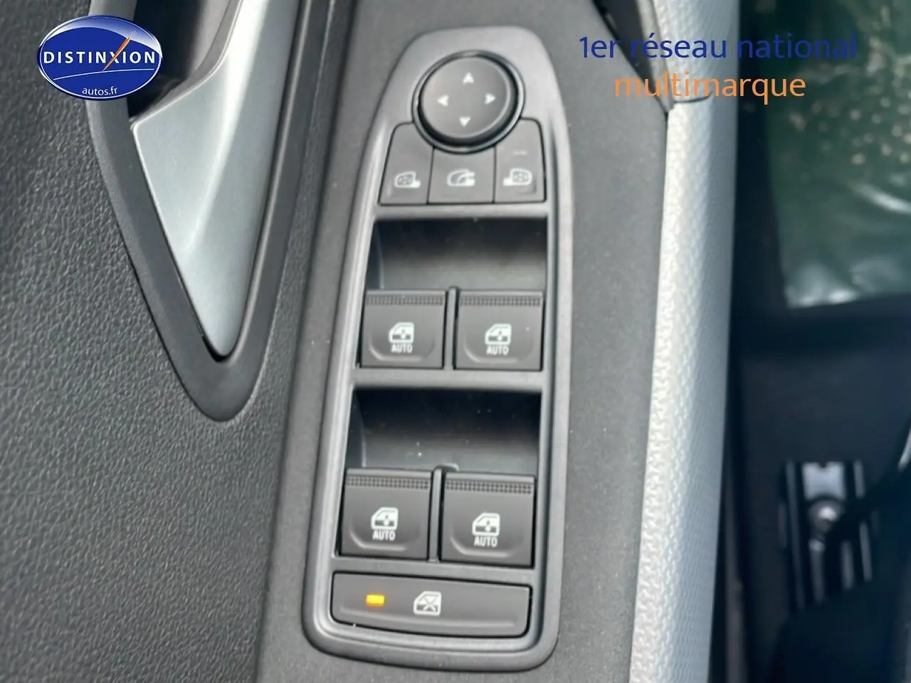 Gros plan sur les commandes des vitres électriques côté conducteur du Dacia Duster 2026, intérieur noir et gris.