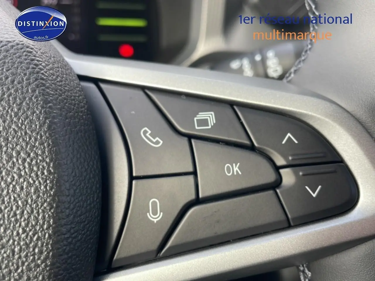 Gros plan sur les commandes multifonctions noires du volant du Dacia Duster 2026, finition Journey vert cèdre.