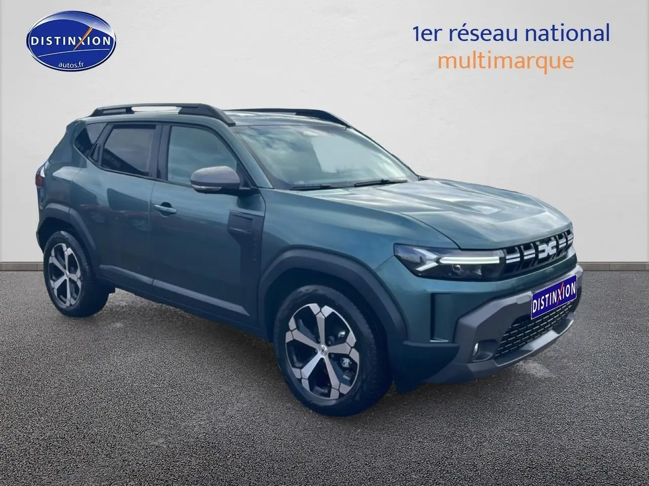 SUV Dacia Duster vert cèdre vu en 3/4 avant droit, avec jantes alu et barres de toit noires.