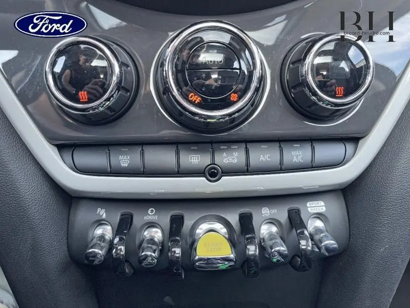 Gros plan sur la console centrale de la MINI Countryman Moonwalk Grey, avec commandes de climatisation et bouton Start/Stop jaune.