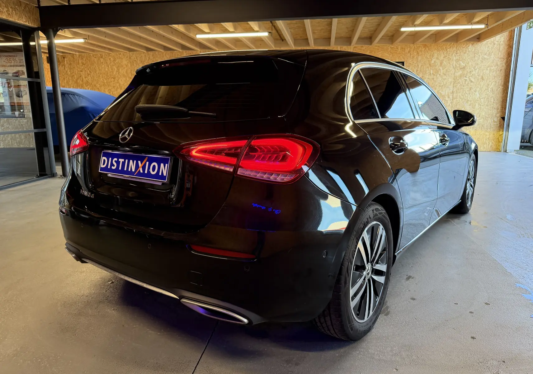 Vue 3/4 arrière droite d'une Mercedes Classe A noire avec feux arrière LED et sorties d'échappement chromées dans un garage.