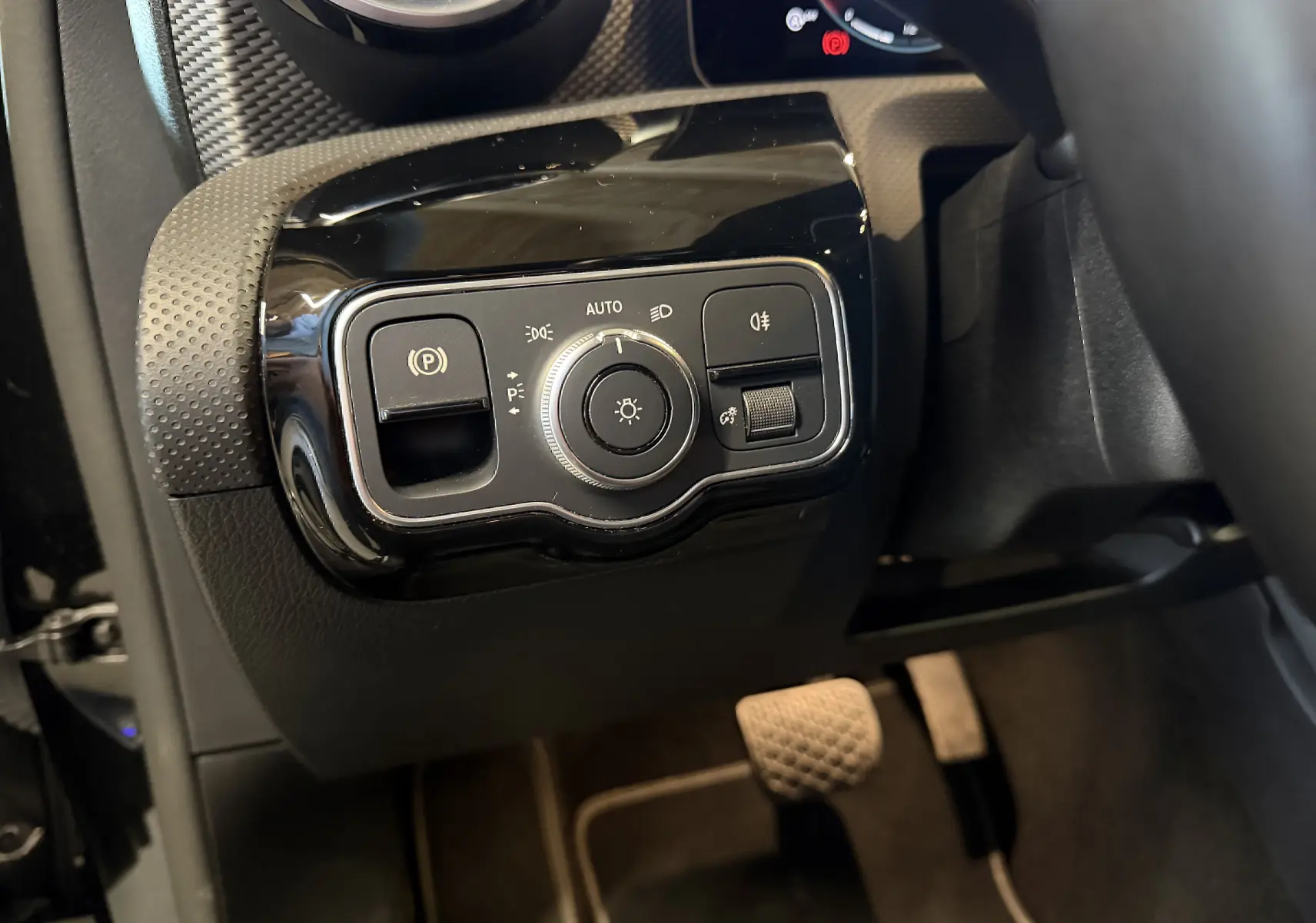 Gros plan sur les commandes d’éclairage noires et brillantes côté gauche du tableau de bord d’une Mercedes Classe A noire 2022.