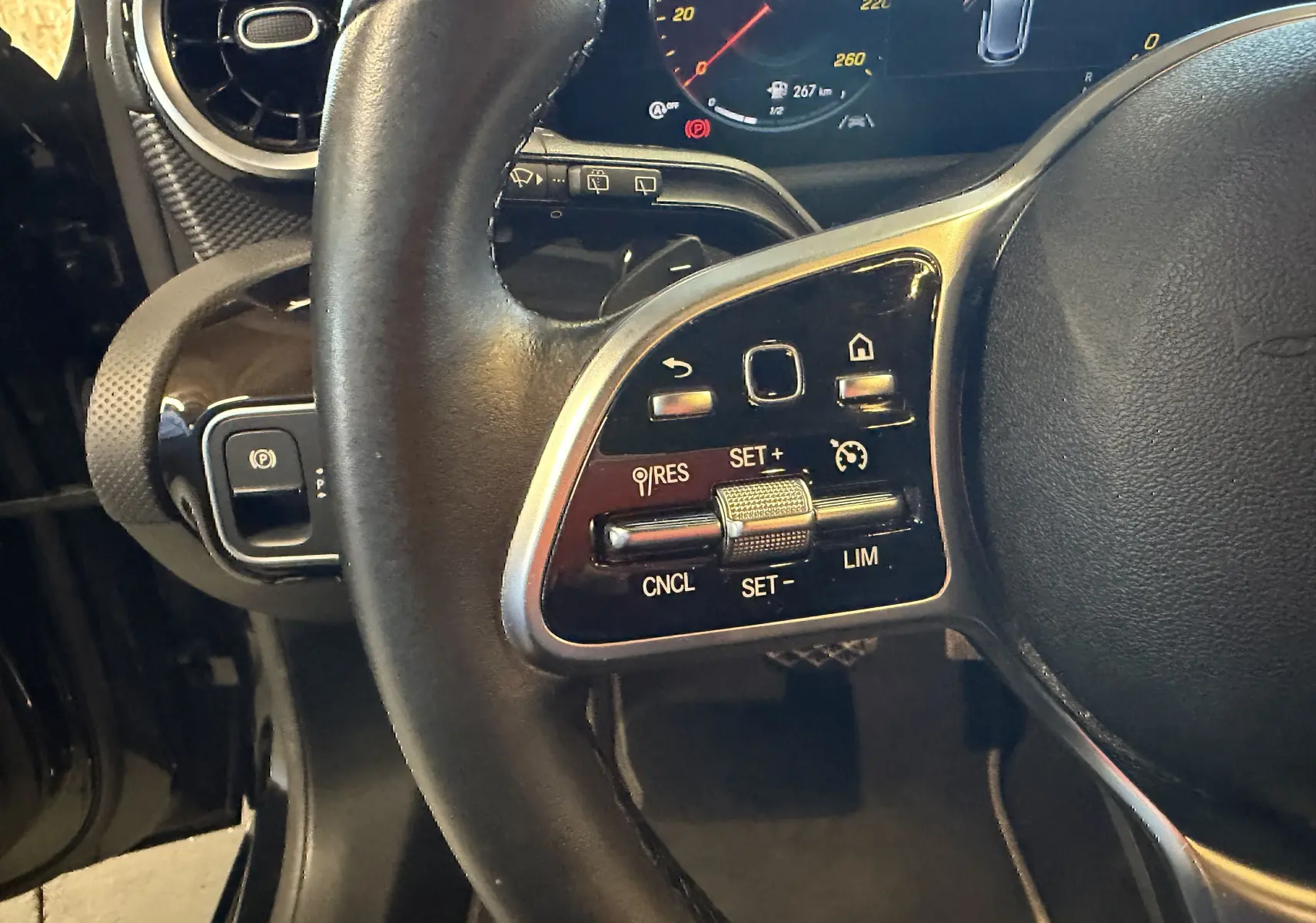 Gros plan sur les commandes multifonctions à gauche du volant cuir noir d'une Mercedes Classe A 2022, tableau de bord numérique visible.