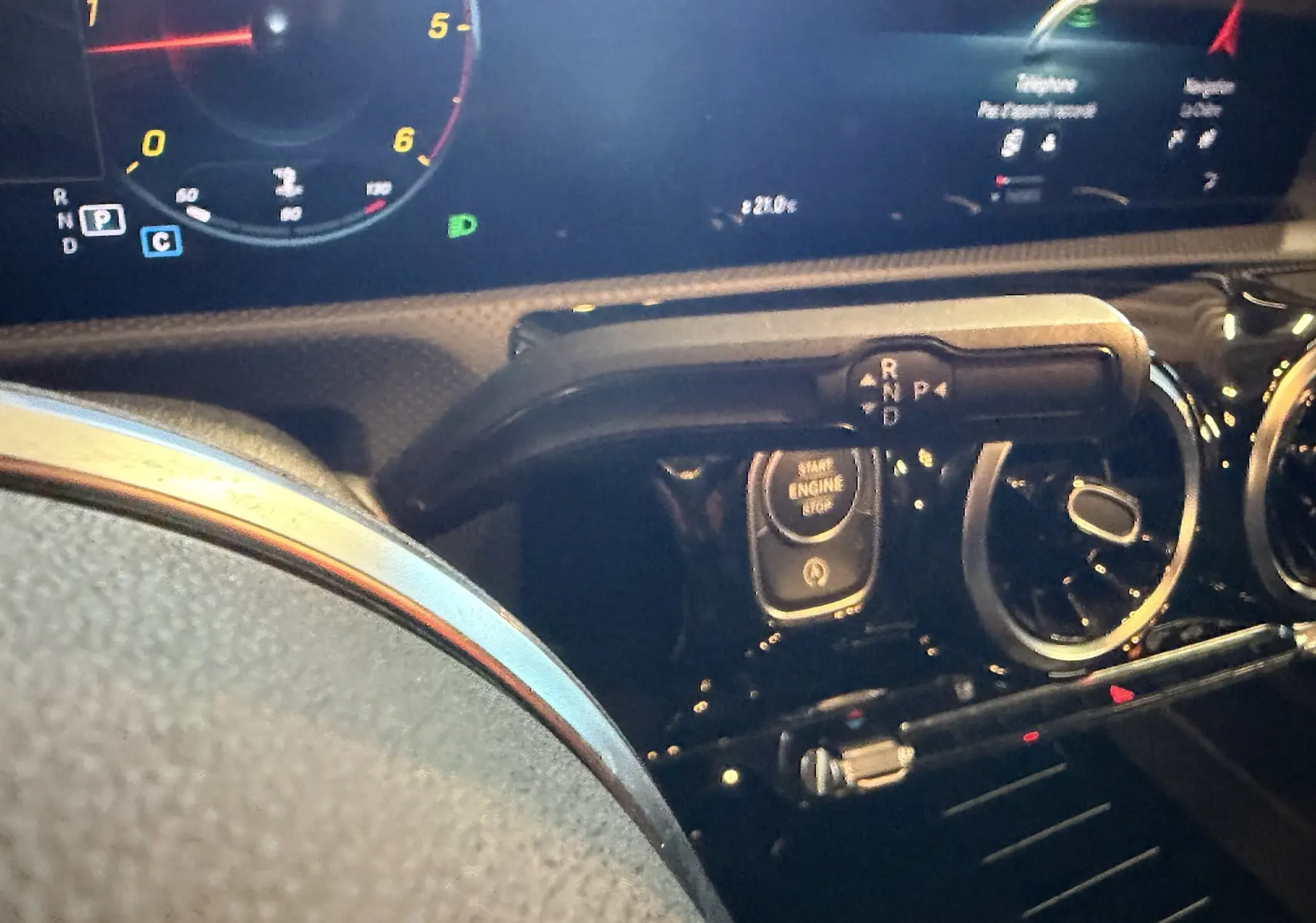 Gros plan sur le tableau de bord noir de la Mercedes Classe A 2022, avec bouton start/stop et levier de vitesses digital.