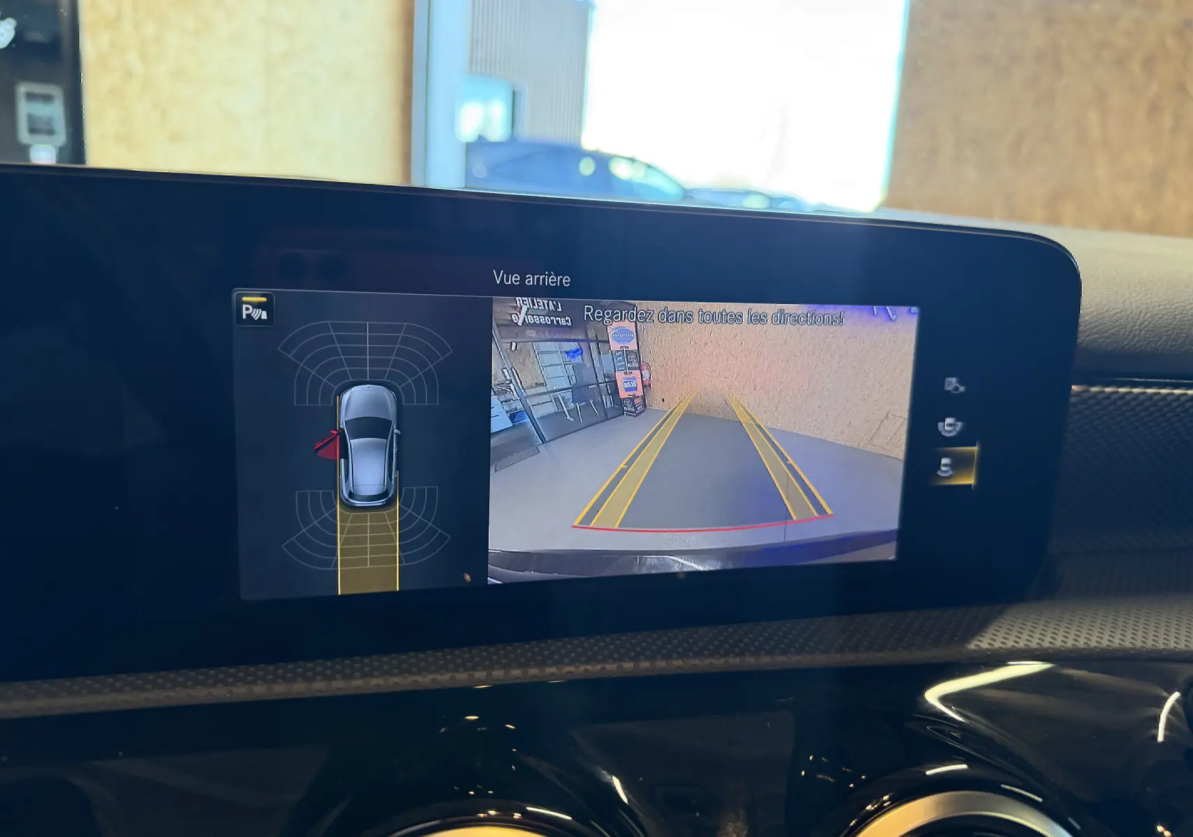 Écran tactile intérieur montrant la caméra de recul et l’aide au stationnement du Mercedes Classe A noir.