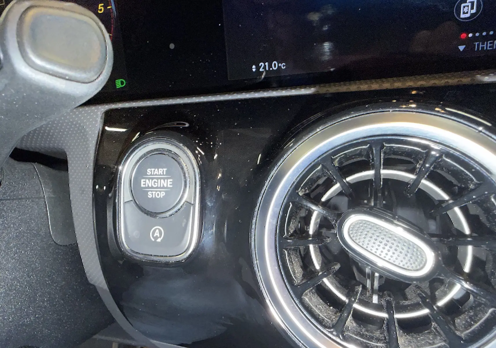 Gros plan sur le bouton Start/Stop et la sortie d’air circulaire chromée du tableau de bord noir d’une Mercedes Classe A 2022.