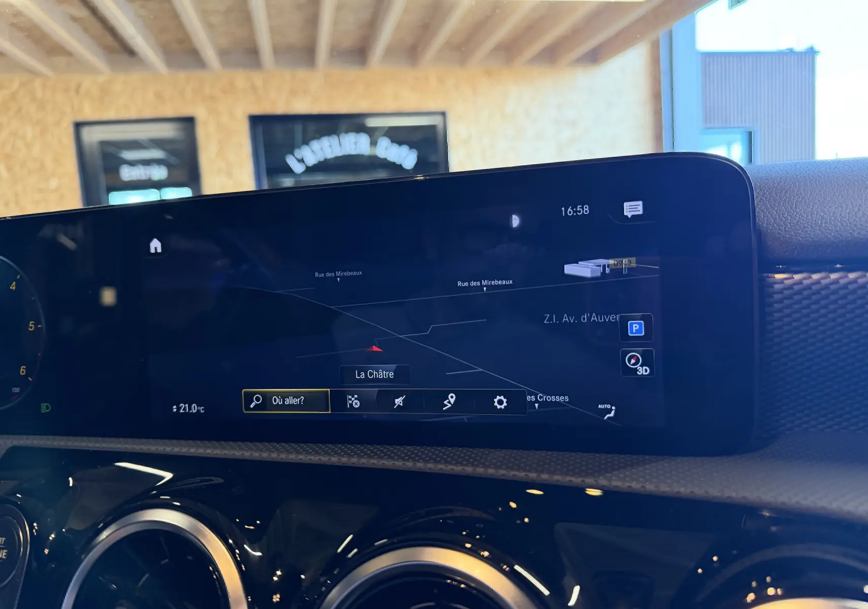 Vue rapprochée de l’écran tactile du GPS intérieur d’une Mercedes Classe A noire, affichant une carte de navigation.