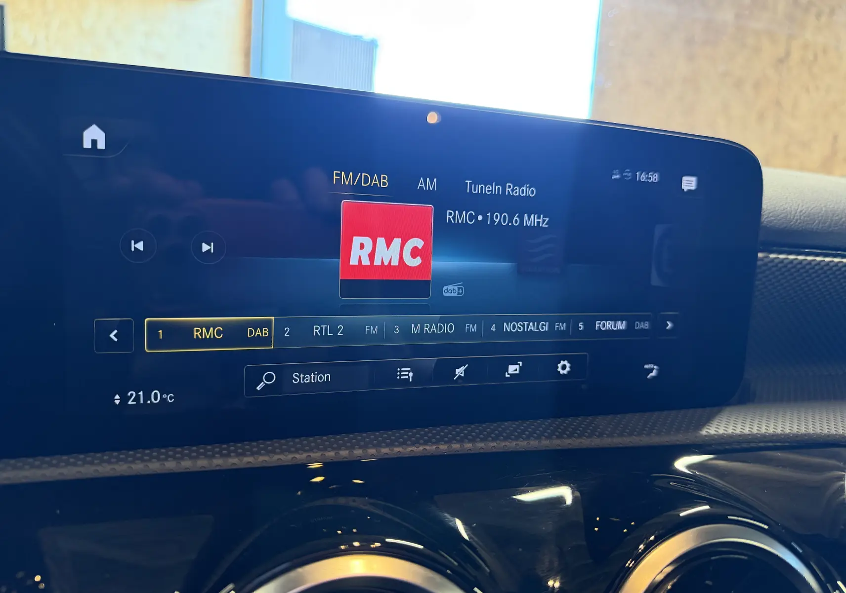 Écran tactile central du tableau de bord d'une Mercedes Classe A noire, affichant la radio FM/DAB sur la station RMC.