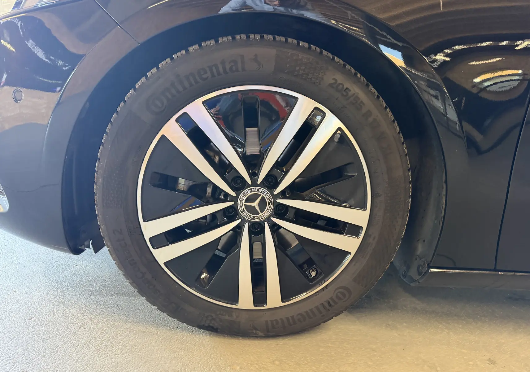 Gros plan sur la jante alu noire et argentée d'une Mercedes Classe A noire, roue avant droite visible.