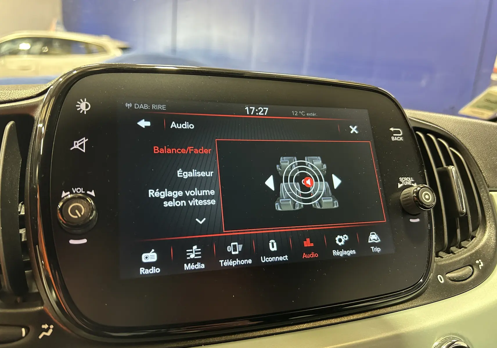 Écran tactile central de la Fiat 500 2023 affichant les réglages audio avec commandes autour en intérieur noir.