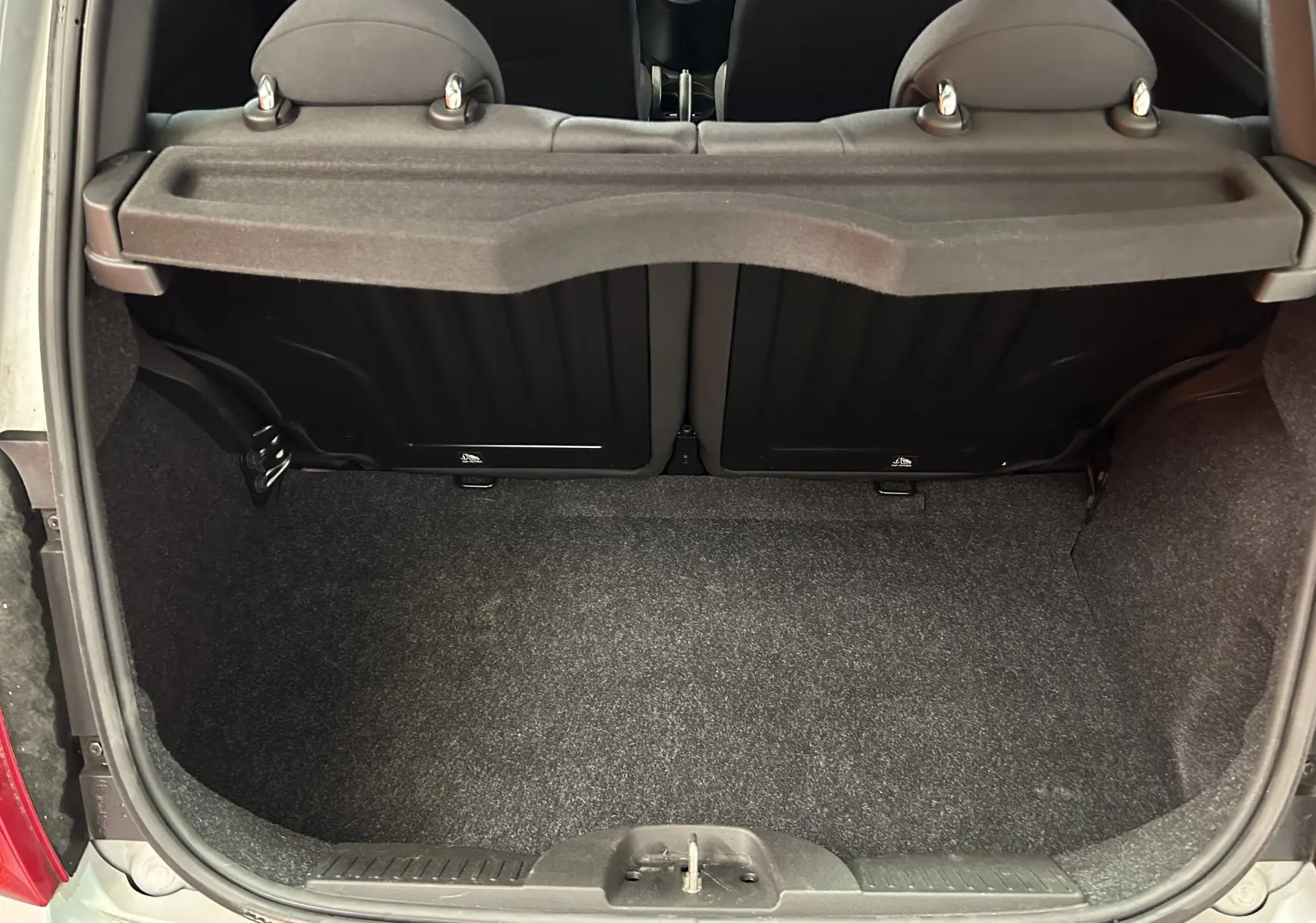 Vue du coffre ouvert d'une Fiat 500 70 Hybride Pack Confort & Style 2023, intérieur noir, sans chargement visible.