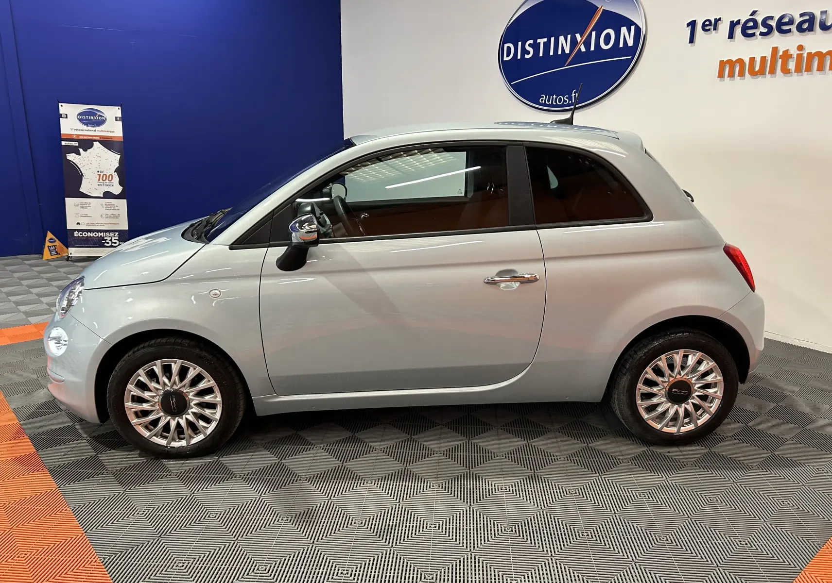 Vue de profil droit d'une FIAT 500 2023 Rugiada Green aux jantes multibranches, dans un showroom intérieur.