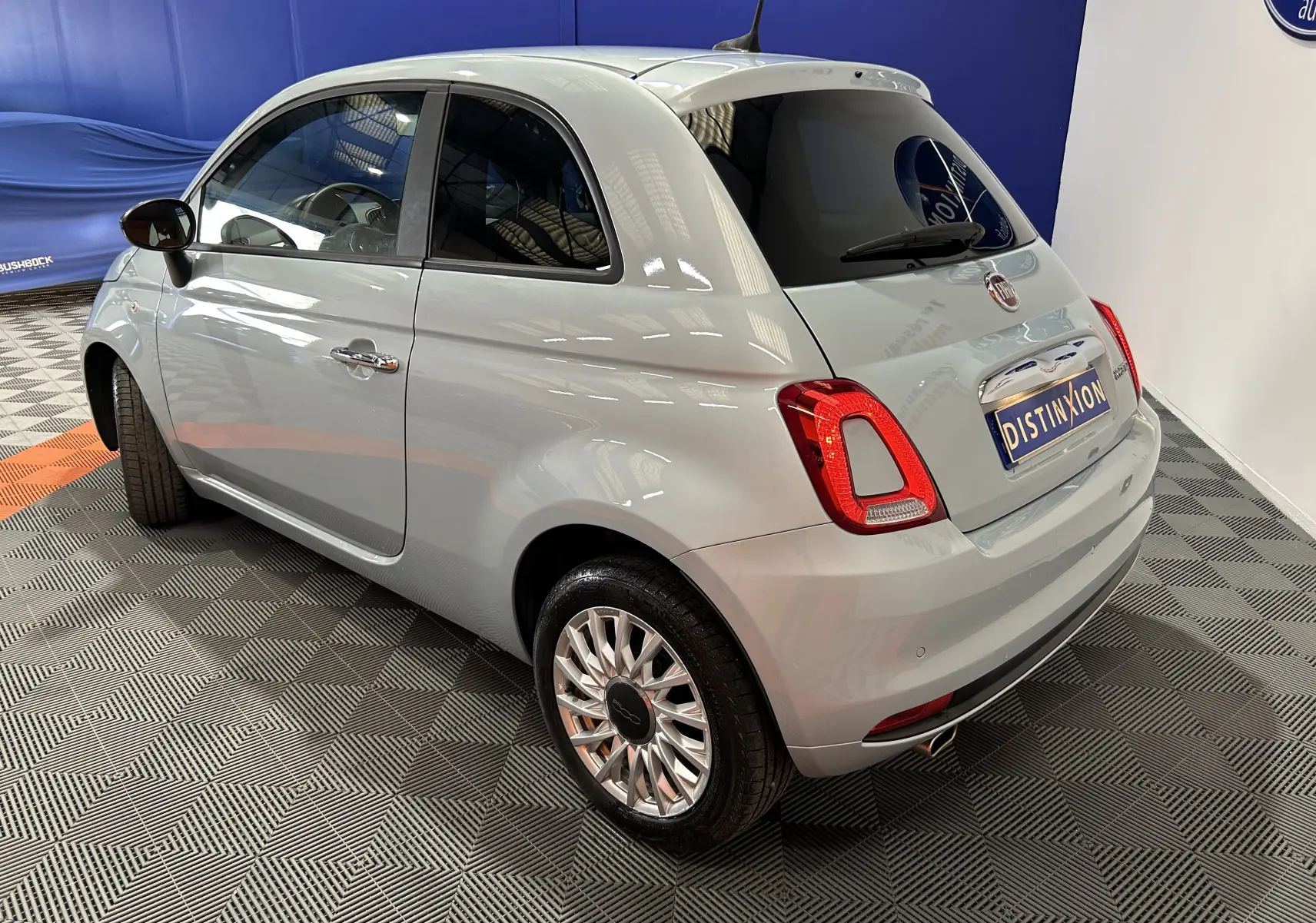 Vue 3/4 arrière droite d'une FIAT 500 2023 couleur vert Rugiada avec jantes alliage et vitres teintées.
