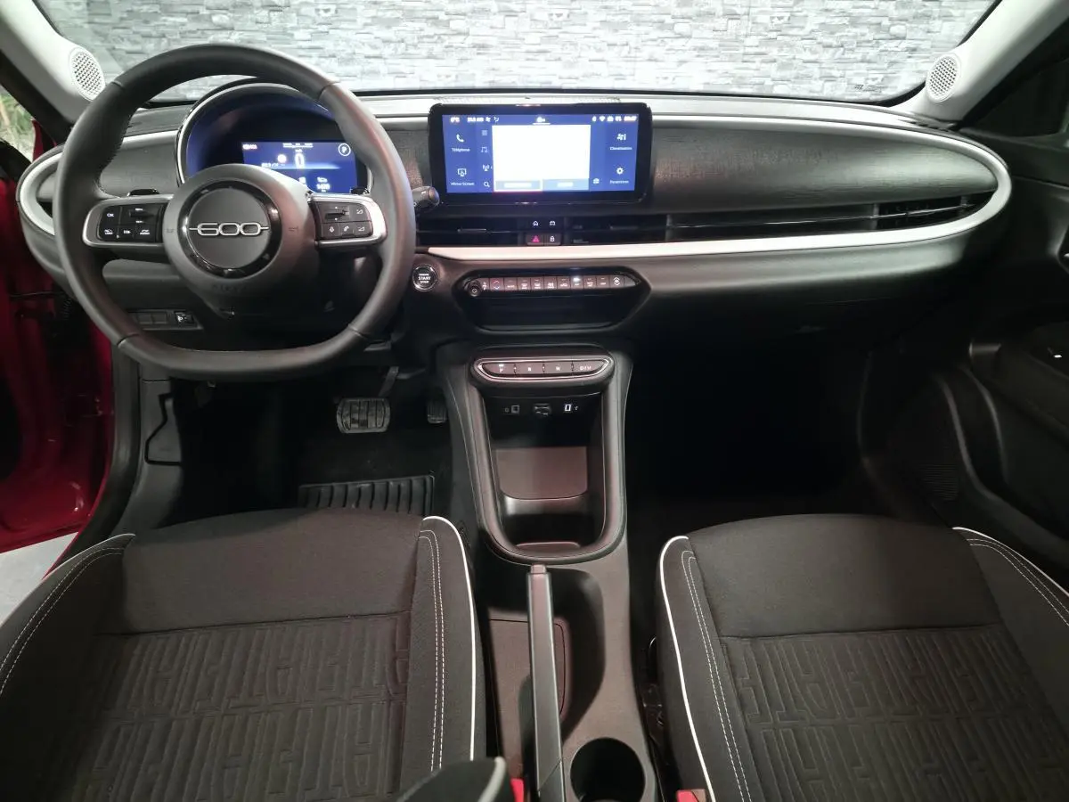 Vue intérieure avant du tableau de bord et volant noir de la FIAT 600 Hybrid 2024 avec écran tactile central.