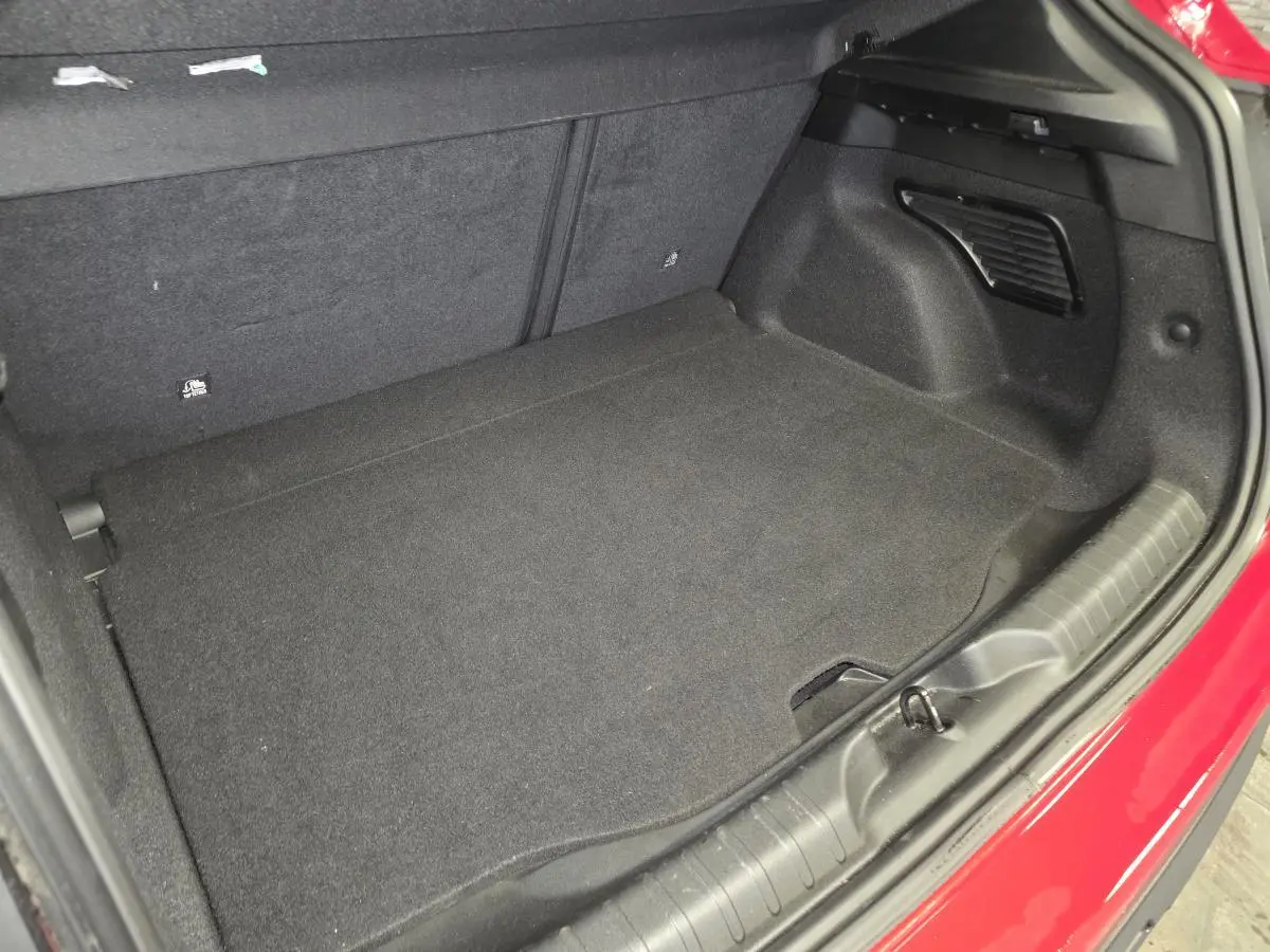 Vue du coffre ouvert de la FIAT 600 Hybrid rouge 2024, montrant l'espace de rangement intérieur noir.