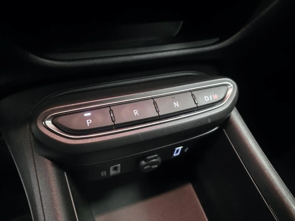 Gros plan sur la console centrale noire avec les boutons de la boîte auto et ports USB visibles d'une Fiat 600 rouge.