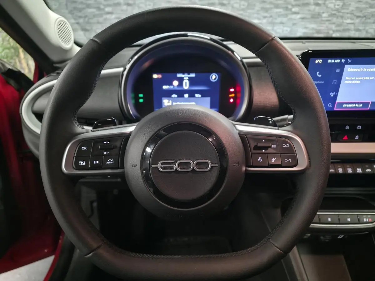 Vue frontale du volant noir de la FIAT 600 2024 avec combiné numérique et écran tactile central.