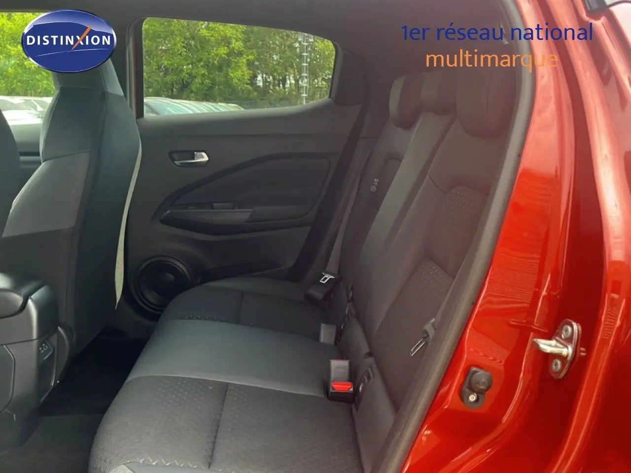 Vue intérieure côté arrière droit du Nissan Juke rouge Fuji Metal 2024, montrant les sièges arrière en tissu noir.