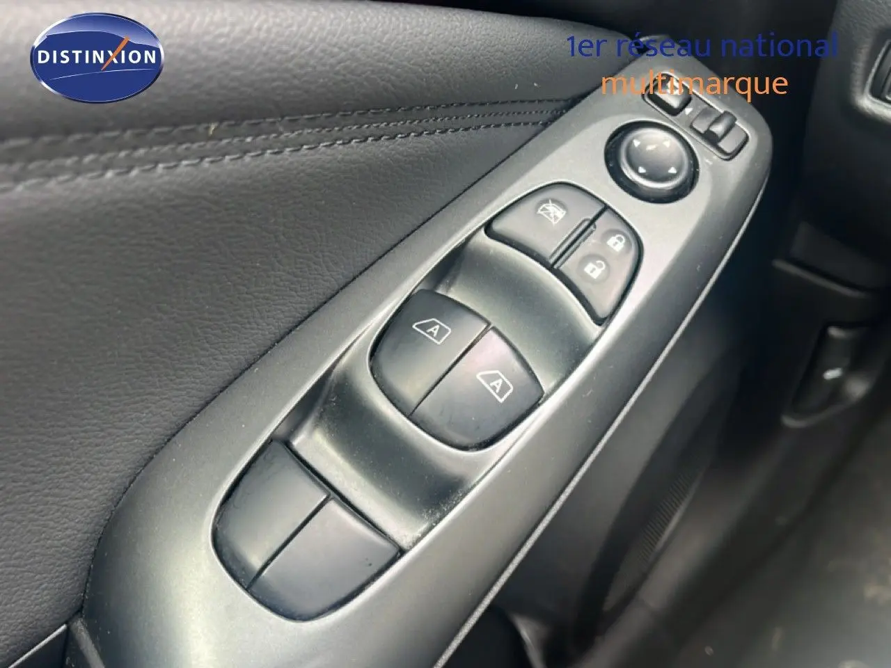 Gros plan sur les commandes des vitres électriques côté conducteur d’un Nissan Juke rouge Fuji Metal 2024.