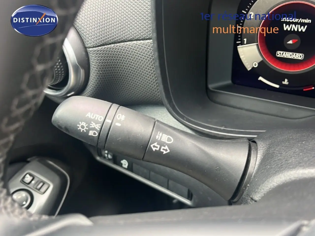 Gros plan sur la commande des feux et clignotants du Nissan Juke 2024, intérieur noir, détails fonctionnels visibles.
