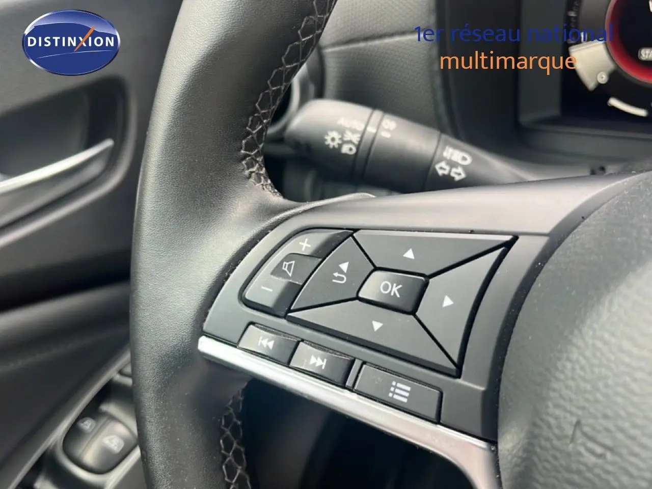 Gros plan sur les commandes au volant côté gauche du Nissan Juke 2024, intérieur noir avec boutons multifonctions.