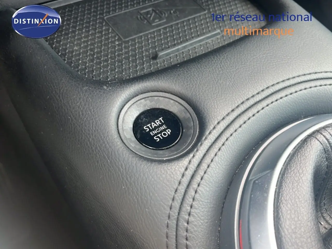 Détail intérieur montrant le bouton Start/Stop et la console en cuir noir du Nissan Juke rouge Fuji Metal 2024.