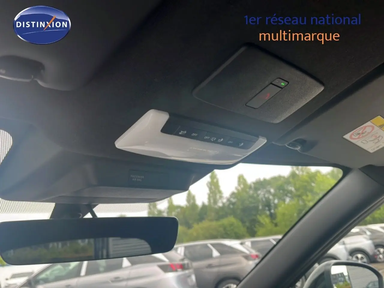 Vue intérieure du toit et rétroviseur d’un Nissan Juke rouge Fuji Metal 2024, avec commandes intégrées au plafond.